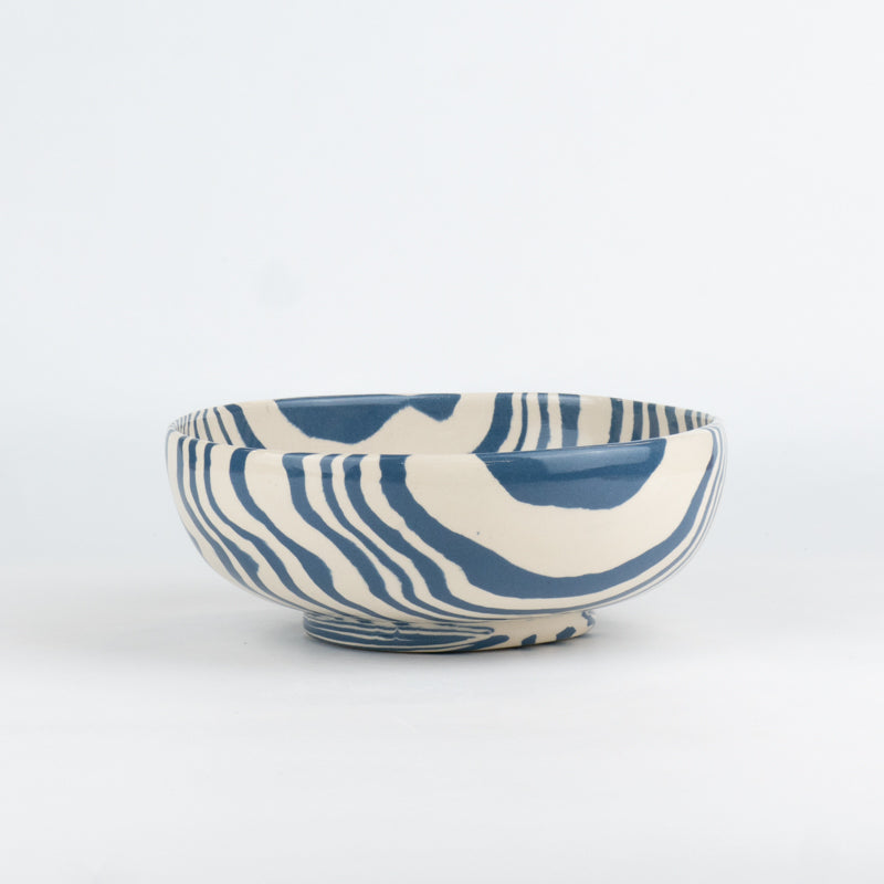 Ceramic bowl with blue and white abstract pattern on a white background